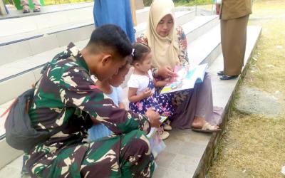 Prada Adnan FZ, anggota Satgas TMMD ke-129 Kodim 0813/Bojonegoro, mendampingi anak-anak membaca buku dalam kegiatan Layanan Terpadu Perpustakaan Desa (LTPD) di Pendopo Balai Desa Kesongo, Kecamatan Kedungadem, Selasa (4/8/2026). Foto : Deni Aripandi/Sumber TMMD Bojonegoro