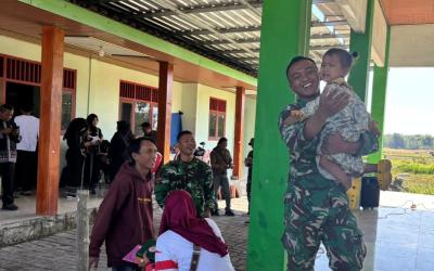 Di halaman Balai Desa Kesongo, seorang prajurit Satgas TMMD tampak menggendong seorang balita sambil bercanda. Tak lama kemudian, anak-anak lainnya ikut mendekat, tertawa, dan bermain bersama para anggota TNI. Suasana yang awalnya dipenuhi kegiatan resmi seketika berubah menjadi hangat dan penuh keceriaan.