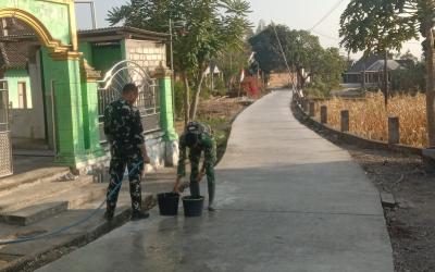 Personel Satgas TNI Manunggal Membangun Desa (TMMD) ke-129 Kodim 0813/Bojonegoro bersama warga melaksanakan perawatan jalan beton yang telah selesai dicor di Dusun Kedungpandan, Desa Kesongo, Kecamatan Kedungadem, Kabupaten Bojonegoro, Minggu (2/8/2026).