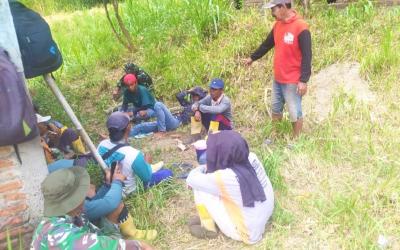 Suasana hangat tampak saat sejumlah prajurit TNI bersama warga memanfaatkan waktu istirahat dengan duduk lesehan di bawah rindangnya pepohonan di tepi jalan. Sambil menunggu kedatangan truk pengangkut material cor beton, mereka menikmati secangkir kopi dan berbincang santai tanpa sekat.