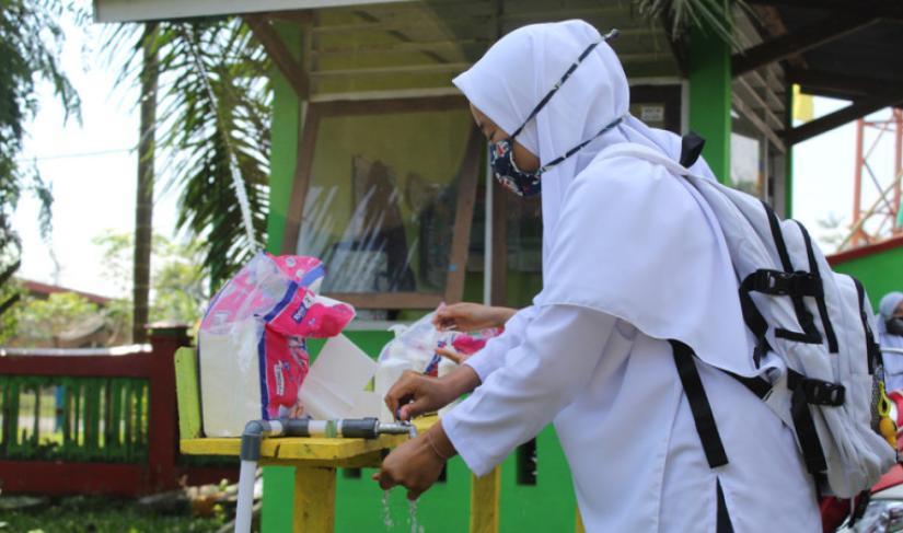 Ilustrasi penggunaan masker dan mencuci tangan sebagai protokol kesehatan.
