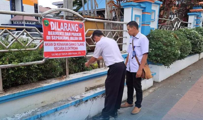 Pegawai Dishub pasang larangan parkir sembarangan di badan jalan.