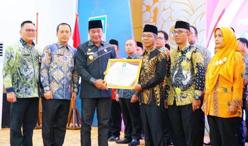 Plt Gubernur Rosjonsyah didampingi Kakanwil Kemenkumham Provinsi Bengkulu, Santosa saat menyerahkan piaga pengukuhan desa/kelurahan sadar hukum di Balai Raya Semarak Bengkulu, Kamis (5/12/2024). (Firza~PenaRafflesia.Com)