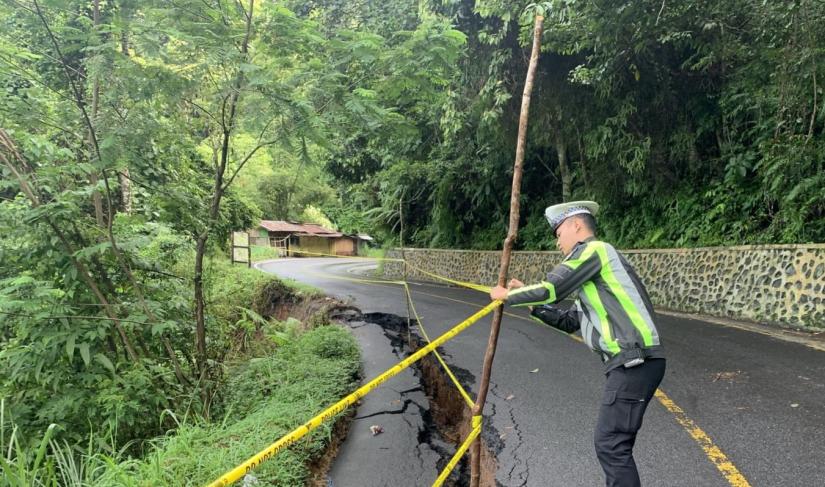 Polisi pasang garis pengaman di lintas Liku Sembilan yang longsor.