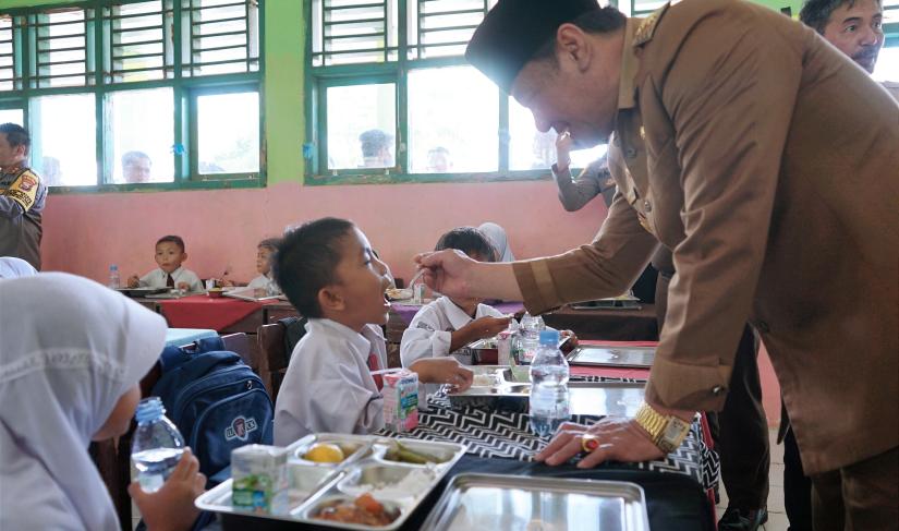 Plt Gubernur Rosjonsyah saat menyuapi siswa dalam kegiatan Makan Siang Sehat Bergizi, Senin (4/11/2024). (Agung-PenaRafflesia.Com)