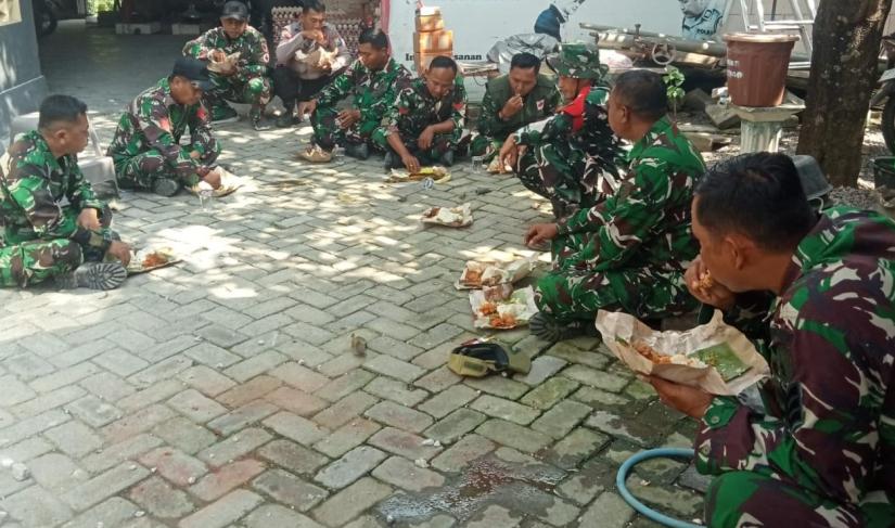 Usai mengerjakan berbagai sasaran fisik, personel Satgas TMMD ke-129 Kodim 0813/Bojonegoro beristirahat sejenak dengan menikmati makan siang menggunakan nasi bungkus sambil duduk lesehan di lokasi pekerjaan, Rabu (22/7/2026).