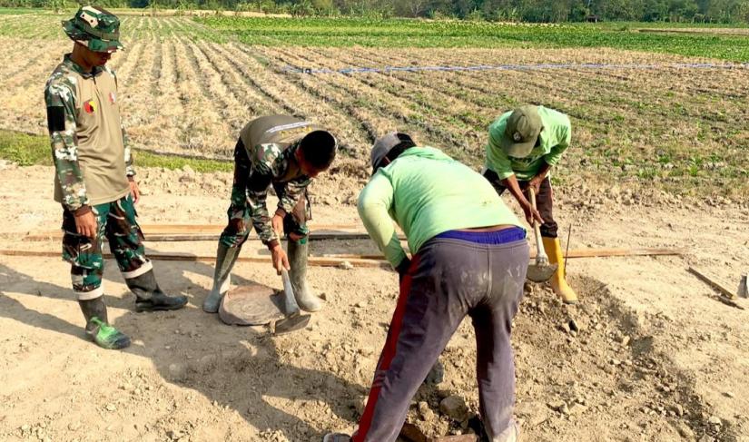 Satgas TMMD ke-129 Kodim 0813 Bojonegoro bersama warga bergotong royong membangun pondasi lapak PKL di kawasan rest area Desa Kesongo, Kecamatan Kedungadem, Kabupaten Bojonegoro.