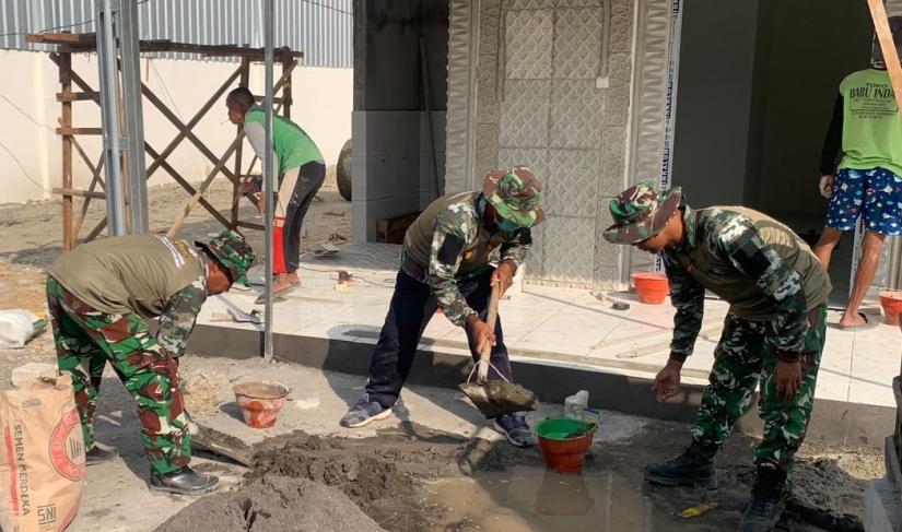 Mushola Masuk Tahap Akhir: Anggota Satgas TMMD ke-129 Kodim 0813 Bojonegoro bersama warga mengerjakan pemasangan keramik teras dan pengecatan mushola di kawasan rest area Desa Kesongo, Kecamatan Kedungadem, Jumat (7/8/2026).