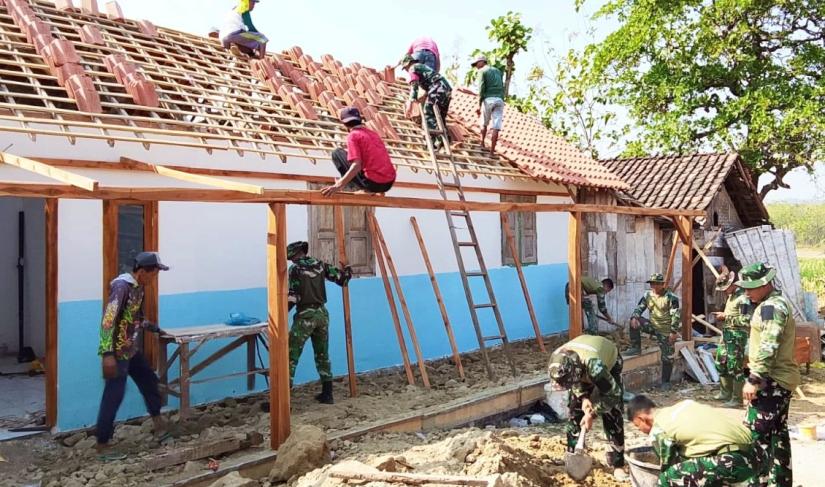 Babinsa Desa Kesongo Serka Lasmidi bersama anggota Satgas TMMD ke-129 Kodim 0813 Bojonegoro dan warga bergotong royong memasang genting pada rumah penerima program RTLH di Desa Kesongo, Kecamatan Kedungadem, Kabupaten Bojonegoro, Minggu (09/08/2026). Foto: Deni Aripandi/Sumber TMMD Bojonegoro.