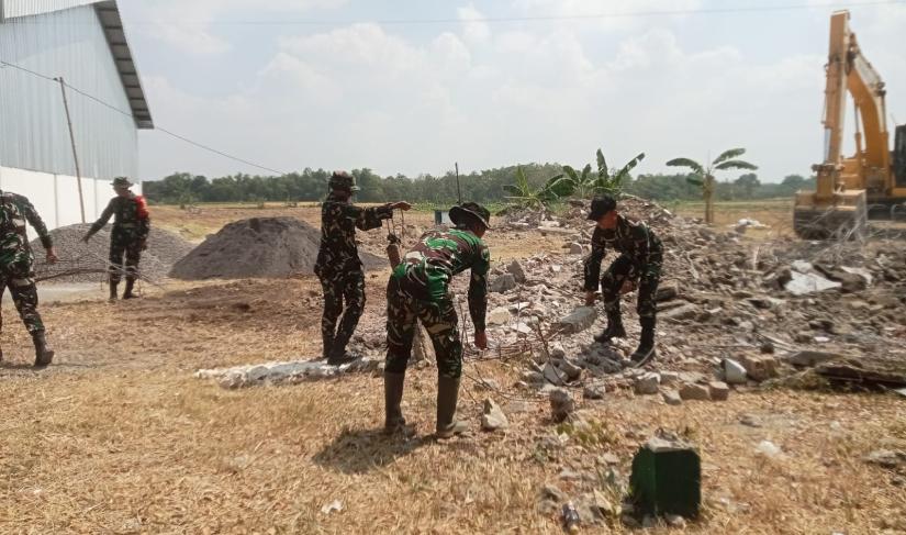 Personel Satgas TMMD bersama warga turun langsung membersihkan puing-puing bangunan lama sebagai tahap awal pembangunan kawasan pujasera (rest area), Sabtu (18/7/2026).