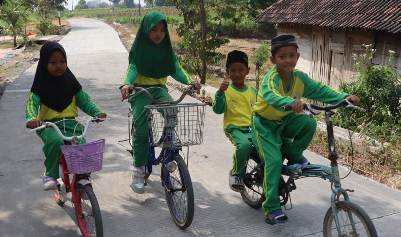 Dengan sepeda yang mereka kayuh penuh semangat, perjalanan menuju sekolah kini terasa lebih nyaman setelah akses jalan di wilayah mereka berubah menjadi lebih baik.