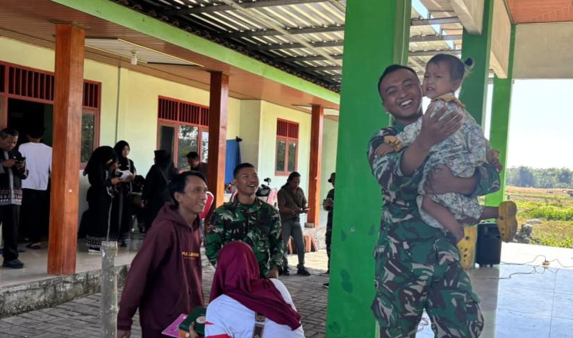 Di halaman Balai Desa Kesongo, seorang prajurit Satgas TMMD tampak menggendong seorang balita sambil bercanda. Tak lama kemudian, anak-anak lainnya ikut mendekat, tertawa, dan bermain bersama para anggota TNI. Suasana yang awalnya dipenuhi kegiatan resmi seketika berubah menjadi hangat dan penuh keceriaan.
