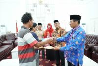 Asisten I Eko Agusrianto menyerahkan bantuan untuk pemindahan makam di Kelurahan Pekan Sabtu kepada 2 orang ahli waris makam, Kamis (11/5/23)