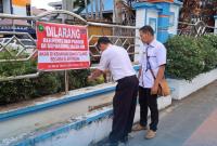 Pegawai Dishub pasang larangan parkir sembarangan di badan jalan.