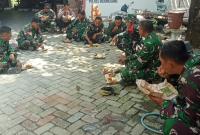 Usai mengerjakan berbagai sasaran fisik, personel Satgas TMMD ke-129 Kodim 0813/Bojonegoro beristirahat sejenak dengan menikmati makan siang menggunakan nasi bungkus sambil duduk lesehan di lokasi pekerjaan, Rabu (22/7/2026).