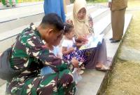 Prada Adnan FZ, anggota Satgas TMMD ke-129 Kodim 0813/Bojonegoro, mendampingi anak-anak membaca buku dalam kegiatan Layanan Terpadu Perpustakaan Desa (LTPD) di Pendopo Balai Desa Kesongo, Kecamatan Kedungadem, Selasa (4/8/2026). Foto : Deni Aripandi/Sumber TMMD Bojonegoro