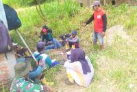 Suasana hangat tampak saat sejumlah prajurit TNI bersama warga memanfaatkan waktu istirahat dengan duduk lesehan di bawah rindangnya pepohonan di tepi jalan. Sambil menunggu kedatangan truk pengangkut material cor beton, mereka menikmati secangkir kopi dan berbincang santai tanpa sekat.