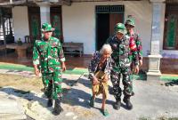 Babinsa Desa Kesongo Serka Lasmidi mendampingi Mbah Kasidah melihat proses rehabilitasi rumah putranya, Bapak Ladi, dalam program TMMD ke-129 Kodim 0813 Bojonegoro di Desa Kesongo, Kecamatan Kedungadem, Jumat (7/8/2026).