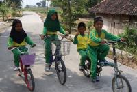 Dengan sepeda yang mereka kayuh penuh semangat, perjalanan menuju sekolah kini terasa lebih nyaman setelah akses jalan di wilayah mereka berubah menjadi lebih baik.